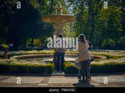 Les parents avec des enfants à l'extérieur debout en face de dépenses fontaine week-end ensemble Banque D'Images