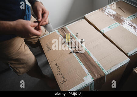 Gros plan d'un homme mûr le choix d'outils de forage tout en mettant l'ensemble de meubles dans sa nouvelle maison. Banque D'Images