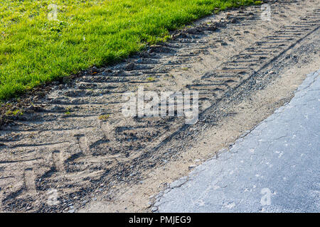 Les traces de pneus du tracteur montrant des dommages à la bordure de la route de pays - la France. Banque D'Images