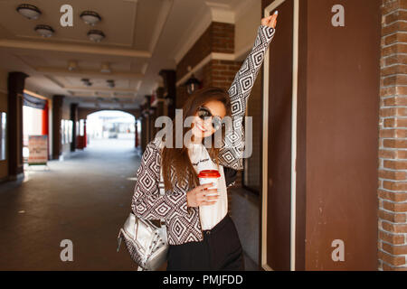 Beautiful happy woman avec café dans une élégante veste est marcher dans la ville Banque D'Images