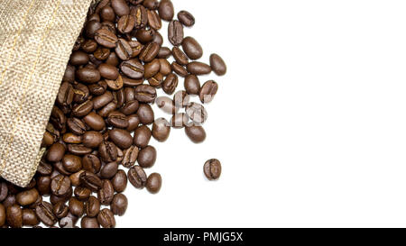 Les grains de café torréfié s'écouler du sac de jute et en surface blanche. Avec l'exemplaire de l'espace. Banque D'Images