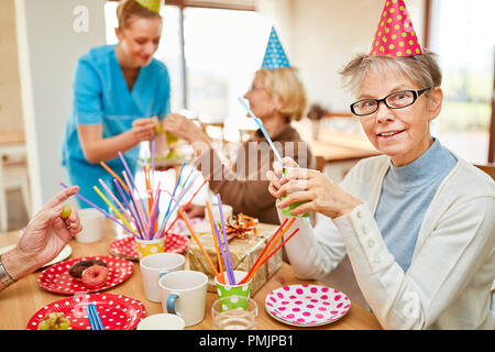 Les aînés s'asseoir ensemble et de boire du café à un anniversaire à la maison de retraite Banque D'Images