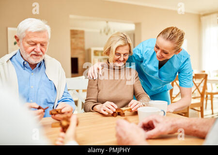 Le fournisseur de soins s'occupe des personnes âgées jouant avec le puzzle en bois Banque D'Images