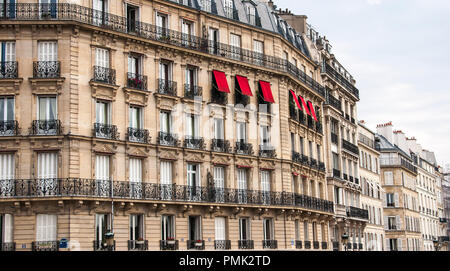 Recouvrir les fenêtres auvents rouges sur un immeuble typiquement parisien avec le noir en fer forgé. Banque D'Images