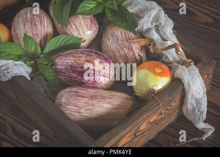 Graffiti violet aubergine, l'oignon vert et le basilic frais dans une boîte en bois dans un fond de bois dans un style rustique, selective focus Banque D'Images