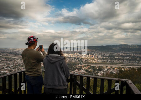 Jeune couple en contemplant la ville de San Salvador de Jujuy à partir d'un point de vue et prendre des photos avec leur téléphone ceular Banque D'Images
