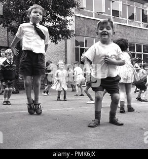 Années 1960, historiques, des enfants de l'école primaire faisant des exercices - Sauts - à l'extérieur dans l'aire de jeux, England, UK. Banque D'Images