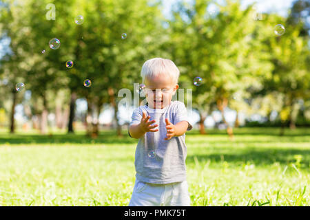 Petit garçon attraper de belles bulles de savon à l'extérieur Banque D'Images