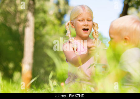 Jolie fille de nourrir un petit enfant dans le parc Banque D'Images