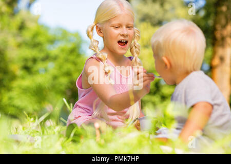 Jolie lycéenne nourrir un enfant dans le parc Banque D'Images