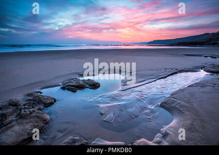 Le lever du soleil sur le sable et les roches à Scarborough dans le Yorkshire du nord de la baie du sud Banque D'Images