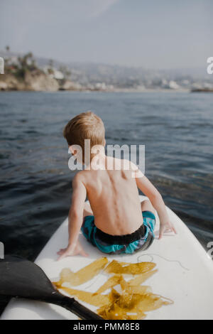 Garçon assis sur un paddleboard, Orange County, United States Banque D'Images