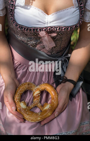 Femme portant un Allemand traditionnel dirndl holding un bretzel Banque D'Images