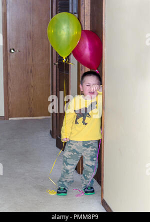 Petit garçon pleurer avec des ballons lors d'une fête Banque D'Images