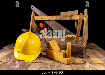 Boîte avec accessoires pour le charpentier. Outils de menuiserie dans une caisse en bois sur une table de l'atelier. Fond sombre. Banque D'Images