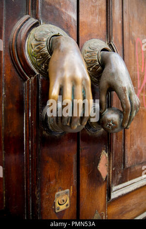 Une paire de heurtoirs de porte en laiton de slender female hands holding oranges placées sur une porte en bois, dans une rue d'Espagnol Banque D'Images