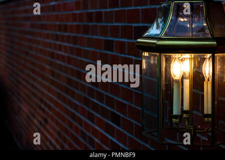 Lampe montée sur un mur de briques d'or d'éclairage la lumière dans les ténèbres Banque D'Images