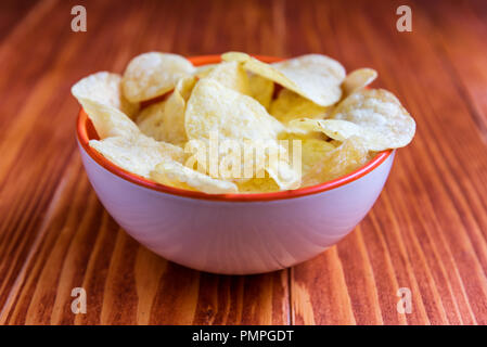 Croustillant de croustilles de pommes de terre dans un bol sur fond de bois Crispy potato chips dans un bol sur fond de bois Banque D'Images
