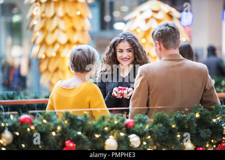 Grand-mère et les petits-enfants senior avec les sacs en papier debout dans un centre commercial au moment de Noël. Banque D'Images