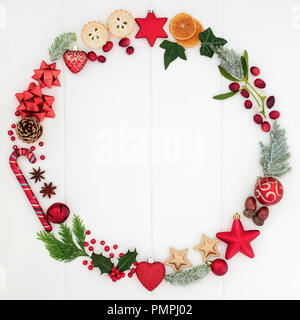 Abstract Christmas wreath garland avec une sélection de symboles traditionnels, y compris la nourriture, de la flore et de décorations babiole sur fond de bois blanc rustique Banque D'Images