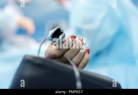 Patients avec un capteur sur l'arrière-plan flou du groupe des médecins dans la salle d'opération. Close up Banque D'Images