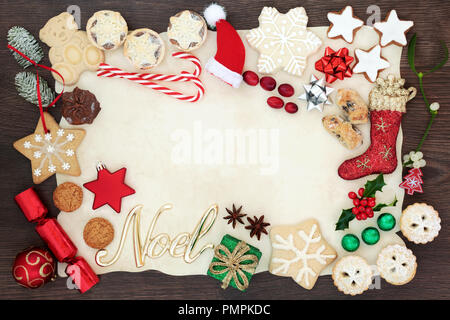 Bordure de l'arrière-plan et noel Noël y compris des décorations de l'arbre, des biscuits, des gâteaux, des fruits, des chocolats et de la flore d'hiver sur le papier parchemin sur chêne rustique. Banque D'Images