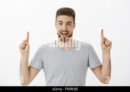 Portrait d'enthousiastes et passionnants brunet sortant avec des hommes en gris barbe occasionnels t-shirt élever les mains vers le haut et vers le haut l'espace copie étonnante discussion posant contre fond blanc Banque D'Images