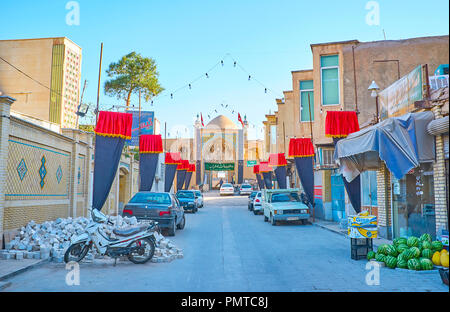 KASHAN, IRAN - le 22 octobre 2017 : La rue étroite avec les étals du marché, Muharram drapeaux et l'iwan (portail) de la mosquée Agha Bozorg sur l'arrière-plan, o Banque D'Images