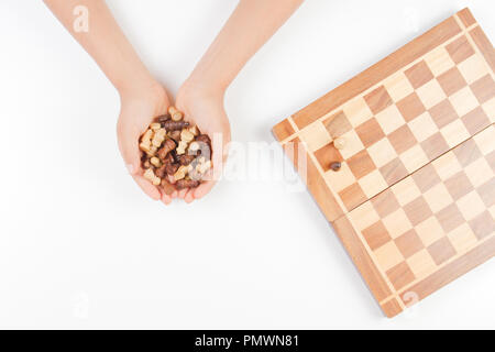 Vue du dessus de l'enfant les mains avec pièces d'échecs et d'échecs sur fond blanc Banque D'Images