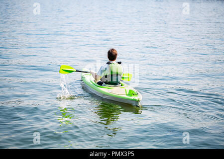 Portrait of mature man paddling kayak dans un lac. Young man canoë sur la journée d'été. Vue arrière Banque D'Images