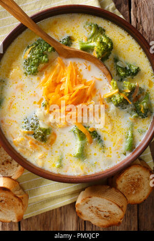 Le brocoli soupe au fromage servi avec du pain grillé close-up dans un bol sur la table. Haut Vertical Vue de dessus Banque D'Images