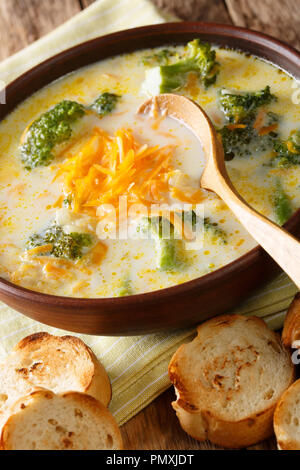 Délicieux fromage cheddar brocoli soupe dans un bol avec du pain grillé libre sur une table verticale. Banque D'Images