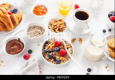 Petit-déjeuner sain avec granola, berry, écrous, croissant, confiture, pâte à tartiner au chocolat et café Banque D'Images