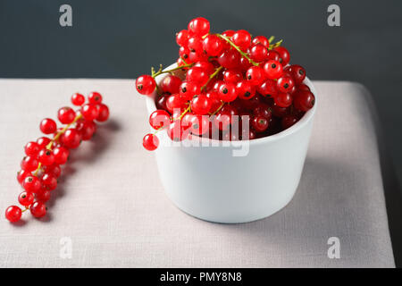 Groseilles rouges dans un bol en porcelaine blanche. Tableau gris, haute résolution Banque D'Images