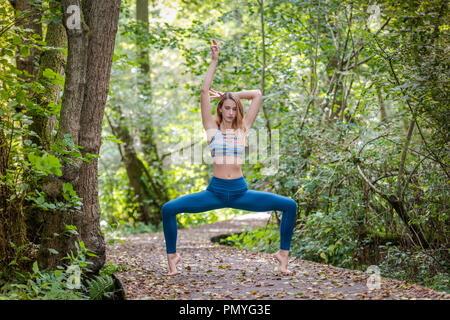 Jeune femme pratiquant le yoga dans les bois sur un trottoir de bois Banque D'Images