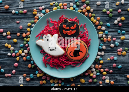 Portrait de la plaque avec les cookies d'halloween entouré de bonbons colorés sur table en bois Banque D'Images