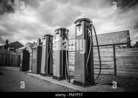 Moody, atmosphère, noir et blanc gros plan de vieilles pompes à essence vintage hors garage vintage, station essence (essence). Des nuages de ciel spectaculaires. Banque D'Images