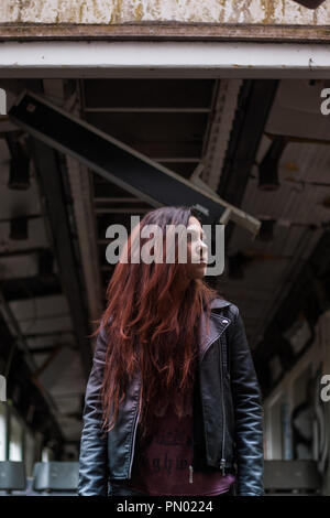 Portrait Jeune femme avec de longs cheveux rouges grounge posant dans une maison abandonnée pleine de graffity Banque D'Images