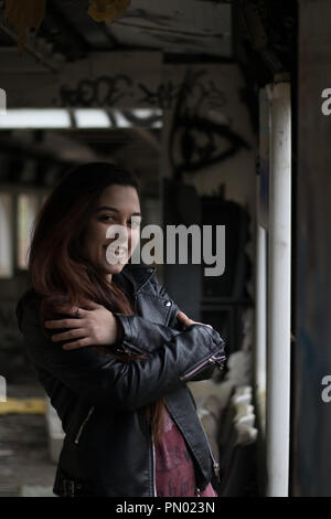 Portrait Jeune femme avec de longs cheveux rouges grounge posant dans une maison abandonnée pleine de graffity Banque D'Images