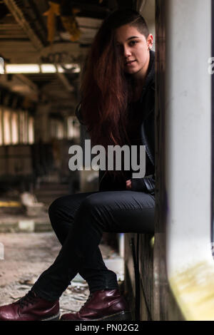 Portrait Jeune femme avec de longs cheveux rouges grounge posant dans une fenêtre ancienne gare abandonnée Banque D'Images