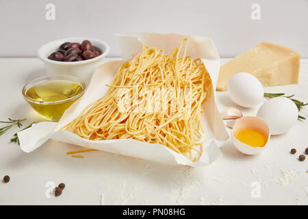 Vue en gros plan d'arrangement de macaroni cuits et autres ingrédients pour la cuisson des pâtes sur la table blanche Banque D'Images