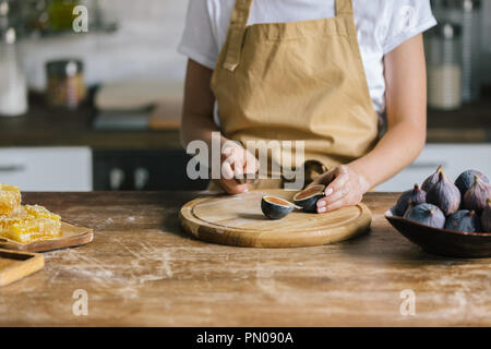 Cropped shot of woman cutting figs sur la table en bois rustique Banque D'Images