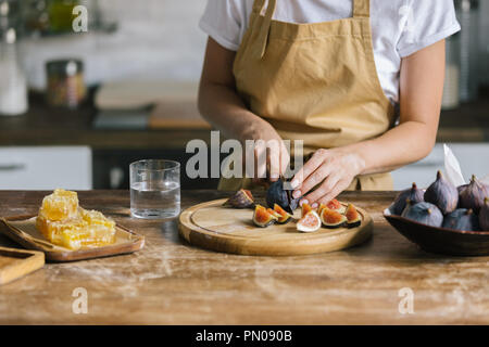 Cropped shot of woman cutting figs pour tarte sur table en bois rustique Banque D'Images