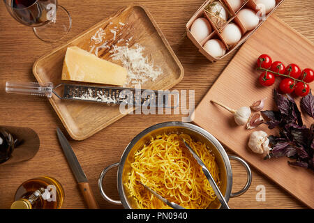 Vue de dessus de spaghetti dans une passoire métallique entouré de divers ingrédients pour les pâtes on wooden table Banque D'Images