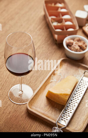 Close-up shot de fromage râpé et un verre de vin rouge sur la table en bois Banque D'Images