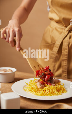 Cropped shot of woman putting sur les pâtes avec sauce spatule en bois Banque D'Images