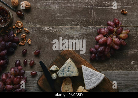 Vue de dessus de raisins frais, noix, fromage et confiture délicieux sur table en bois Banque D'Images