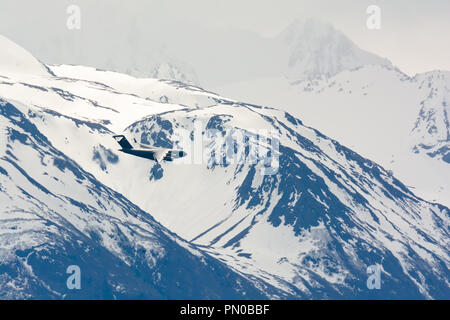 Un avion C-17 de l'USAF est le tournant en face d'une montagne enneigée en Alaska. Banque D'Images
