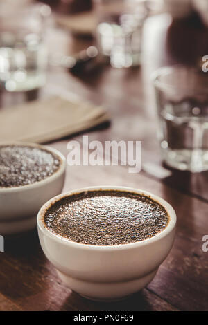 Des grains de café avec de l'eau chaude dans la tasse en céramique sur la table se prépare pour les essais de niveleuse Q professionnel et l'inspection de la qualité du café. Banque D'Images