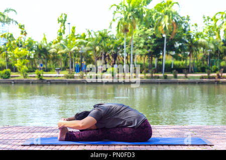 D'âge moyen en bonne santé asian woman sitting in assis vers l'exercice ou paschimottanasana yoga pose au parc de la ville à le matin. en bonne santé et lifest Banque D'Images